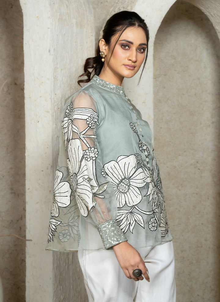 Woman wearing a dusty blue embroidered coord set with floral patterns.