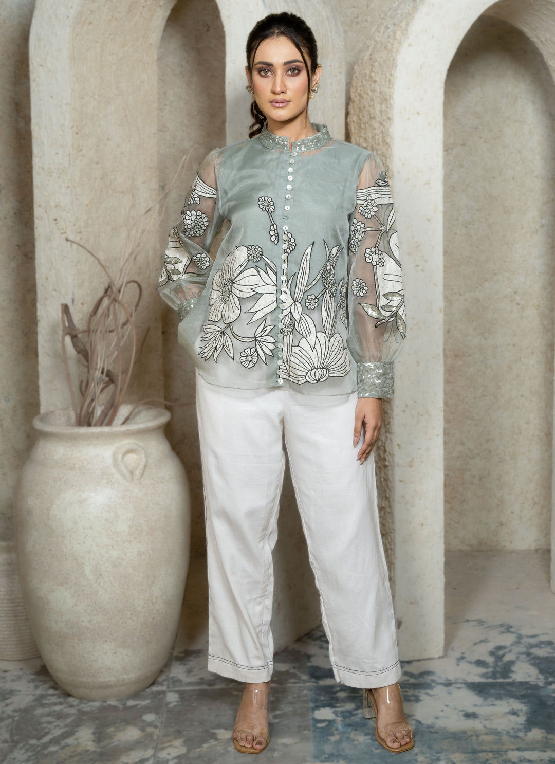 Woman wearing a dusty blue embroidered coord set with floral patterns along with white pants