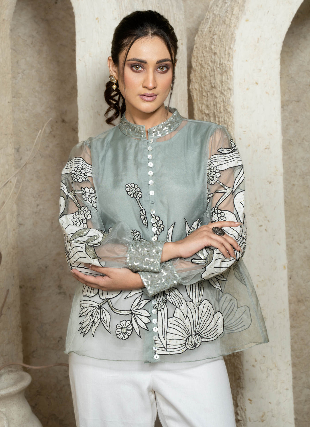Woman wearing a dusty blue embroidered coord set with floral patterns.