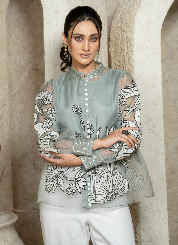 Woman wearing a dusty blue embroidered coord set with floral patterns.