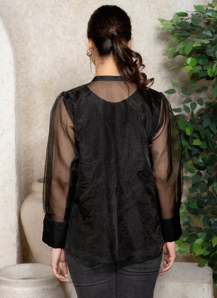 Person wearing a black sheer top with a plain background