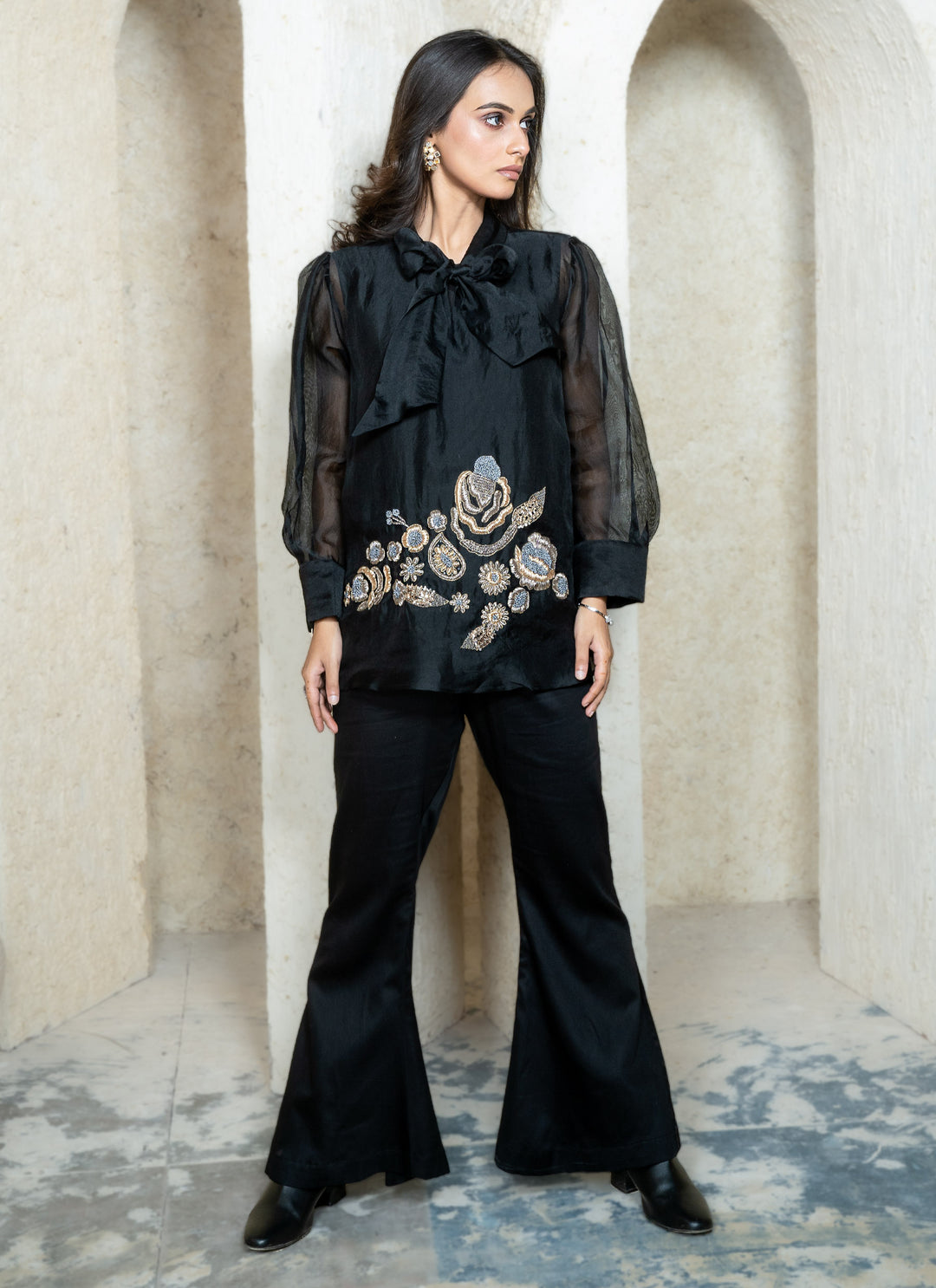Woman wearing a black zardozi outfit with floral embroidery in an architectural setting