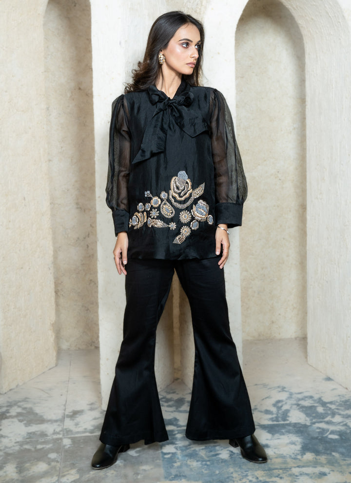 Woman wearing a black zardozi outfit with floral embroidery in an architectural setting