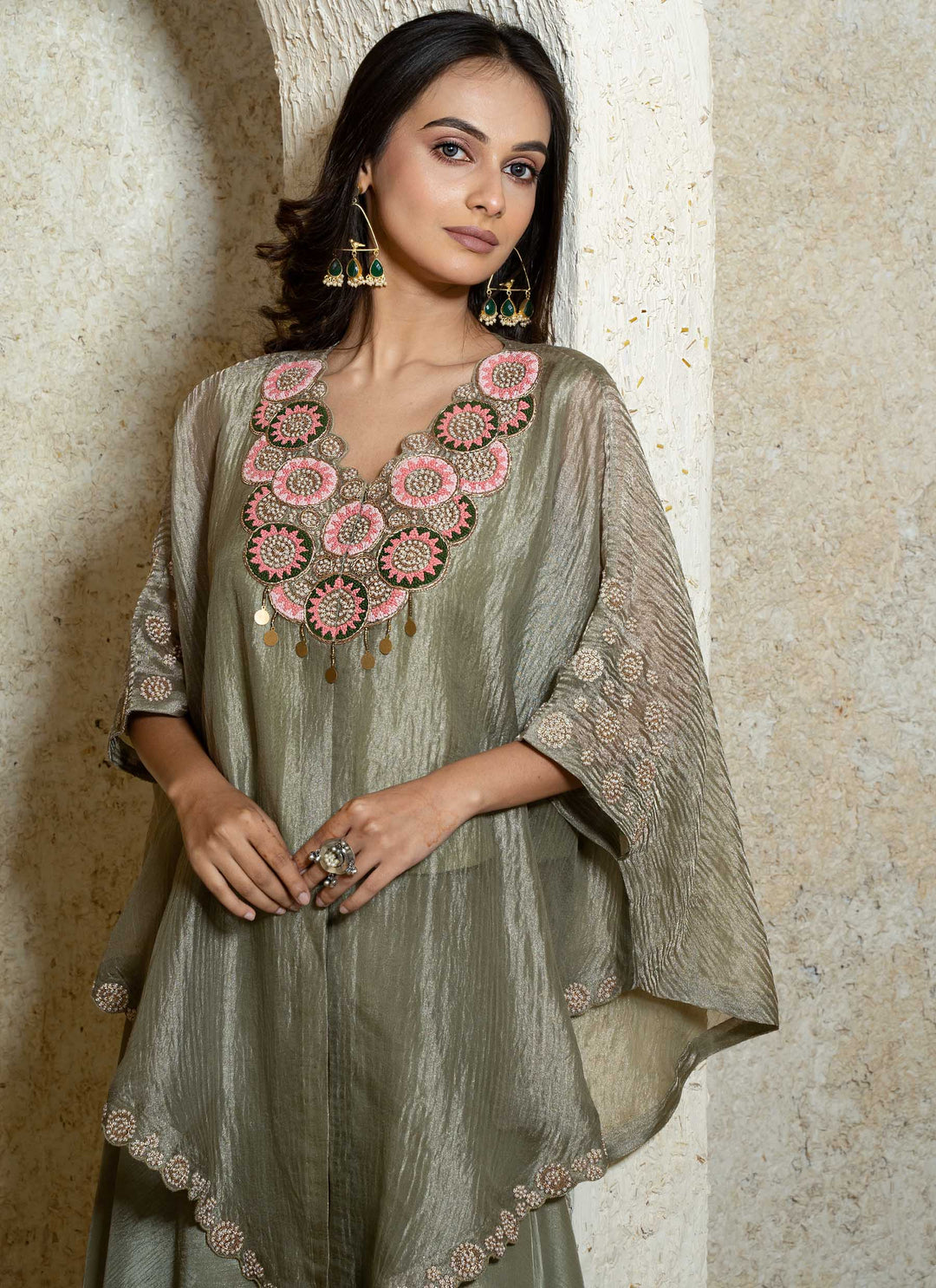Woman wearing a kaftan outfit with intricate embroidery against a neutral background
