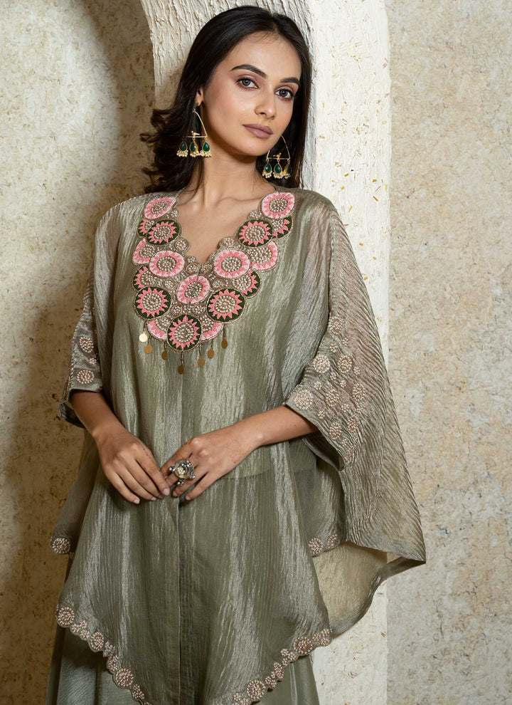 Woman wearing a kaftan outfit with intricate embroidery against a neutral background