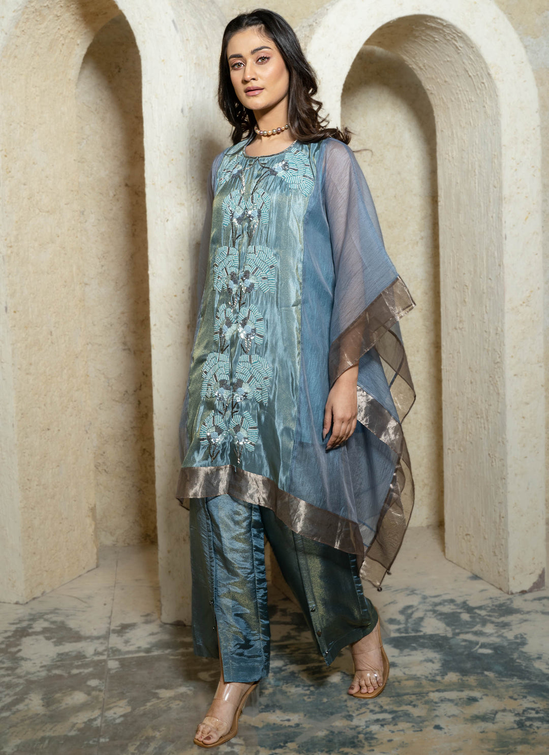 Woman wearing a blue embroidered kaftan set with a beige background