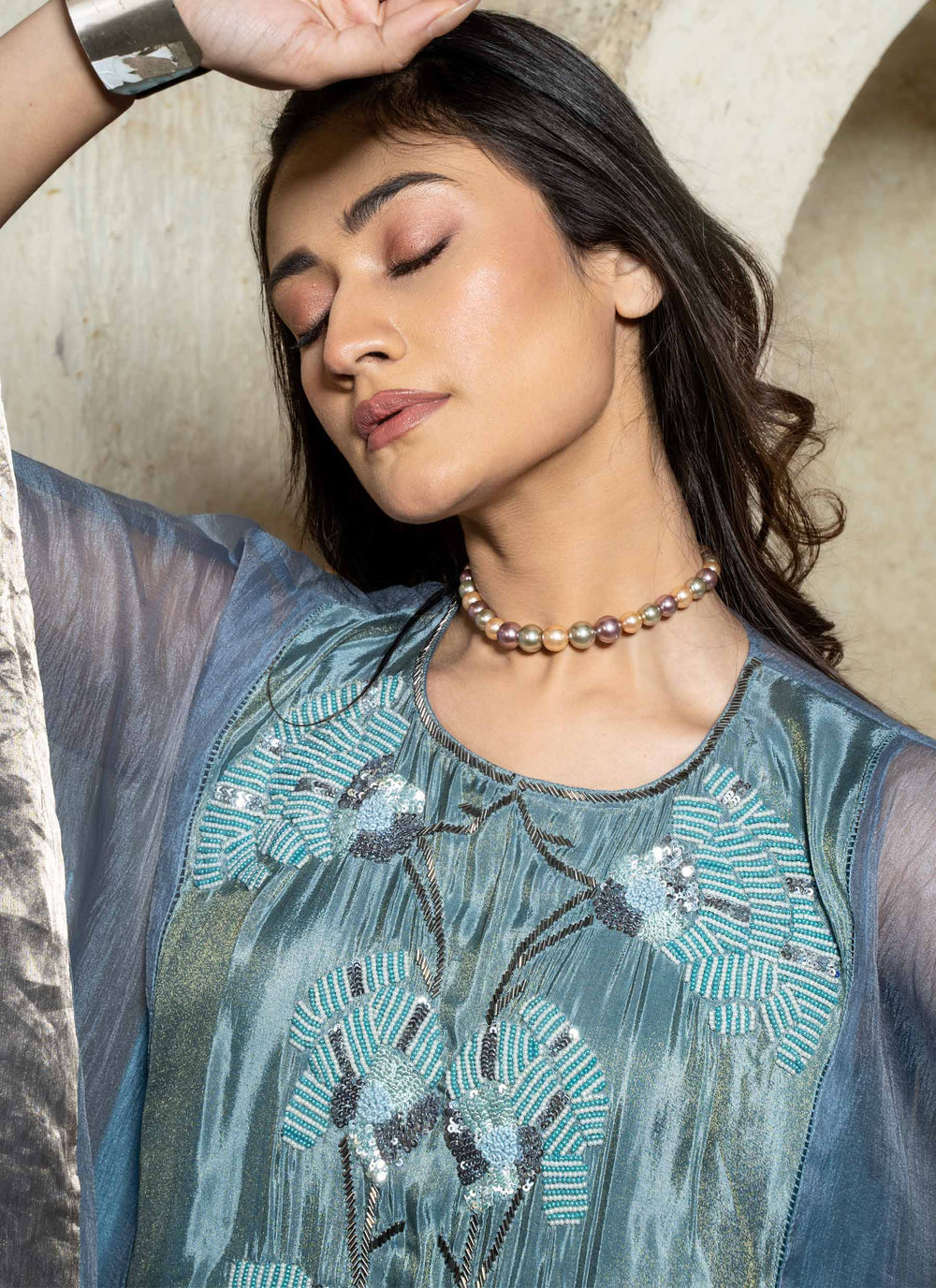 Woman wearing a blue embroidered kaftan set with a beige background