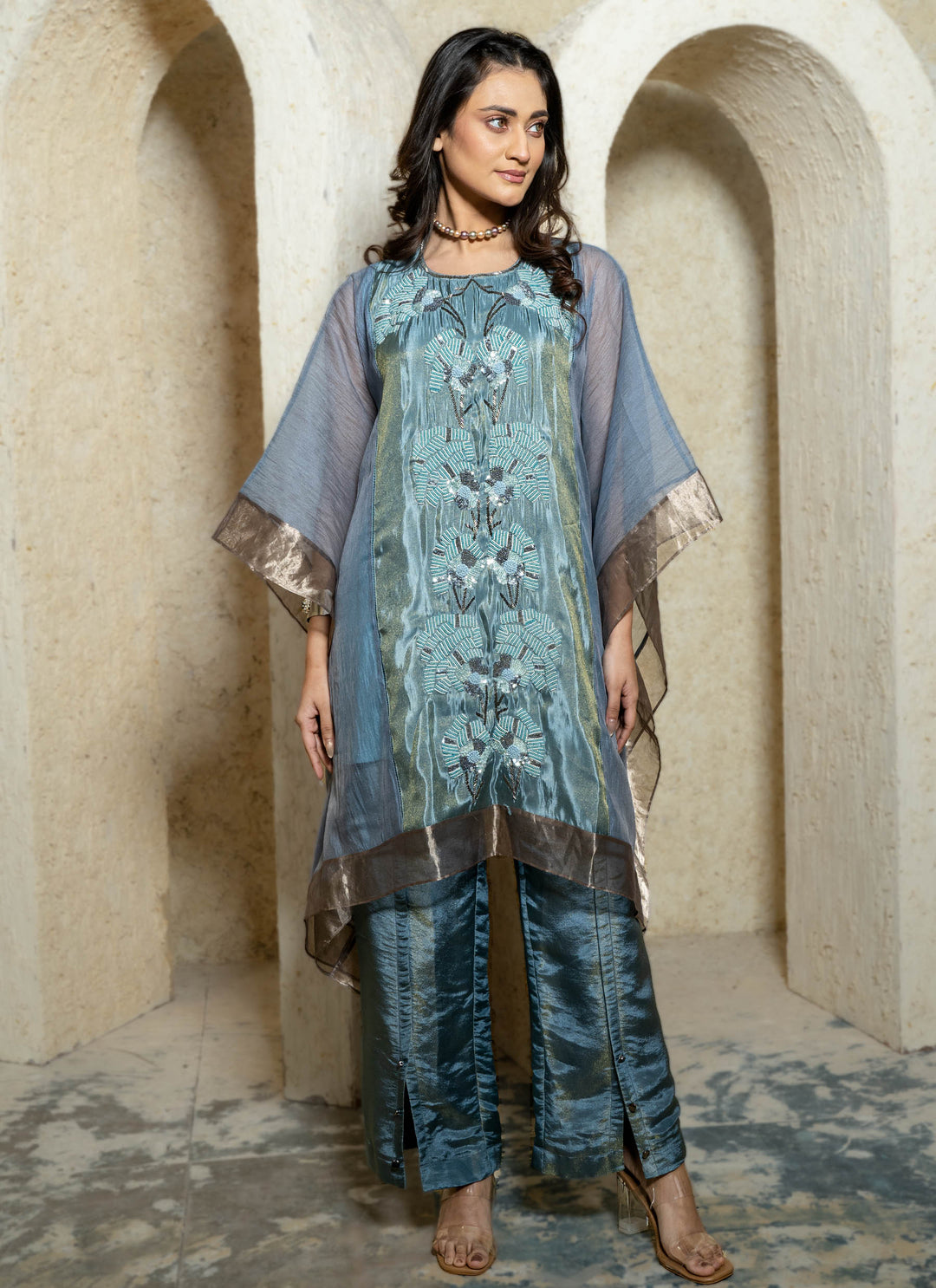 Woman wearing a blue embroidered kaftan set with a beige background