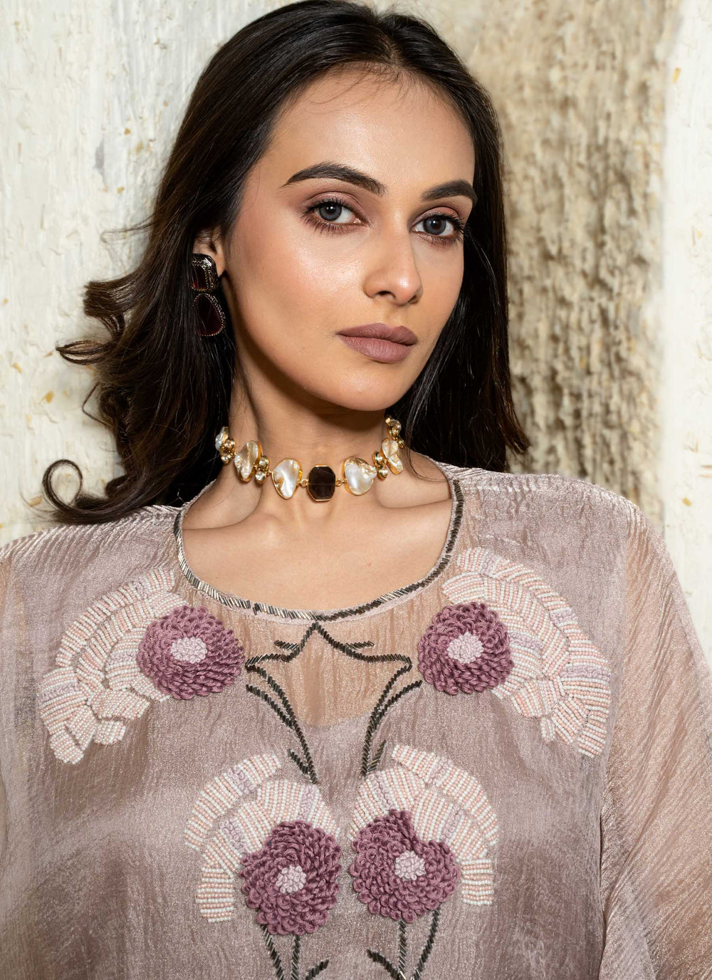 Woman in a pink floral hand embroidered kaftan outfit standing in an archway