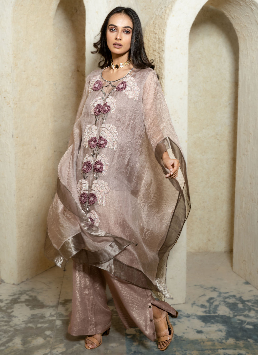 Woman in a pink floral hand embroidered kaftan outfit standing in an archway