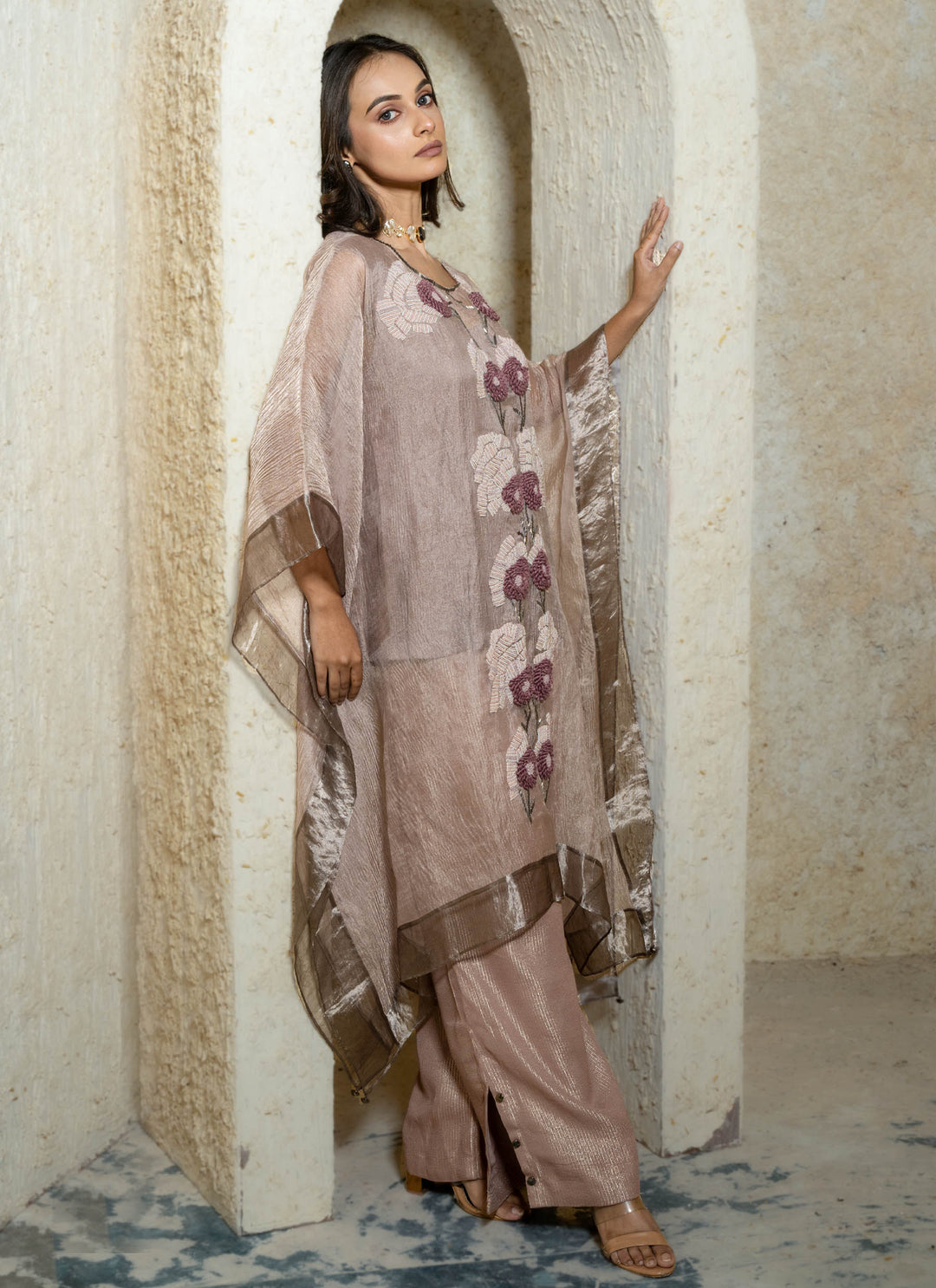 Woman in a pink floral hand embroidered kaftan outfit standing in an archway