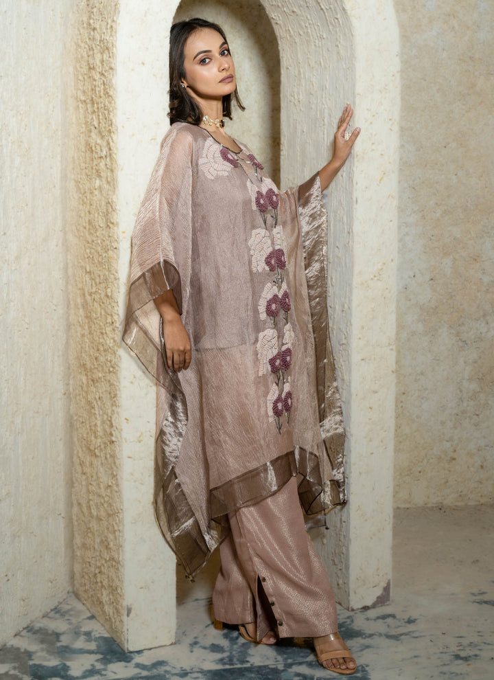 Woman in a pink floral hand embroidered kaftan outfit standing in an archway