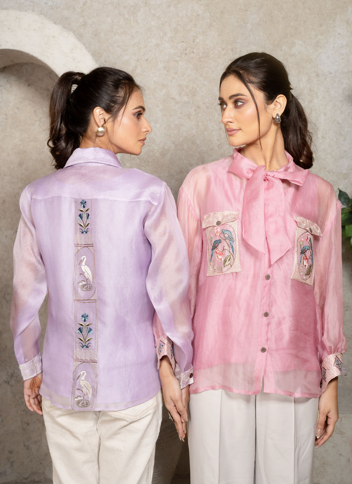 Two women wearing embroidered shirts against a neutral background