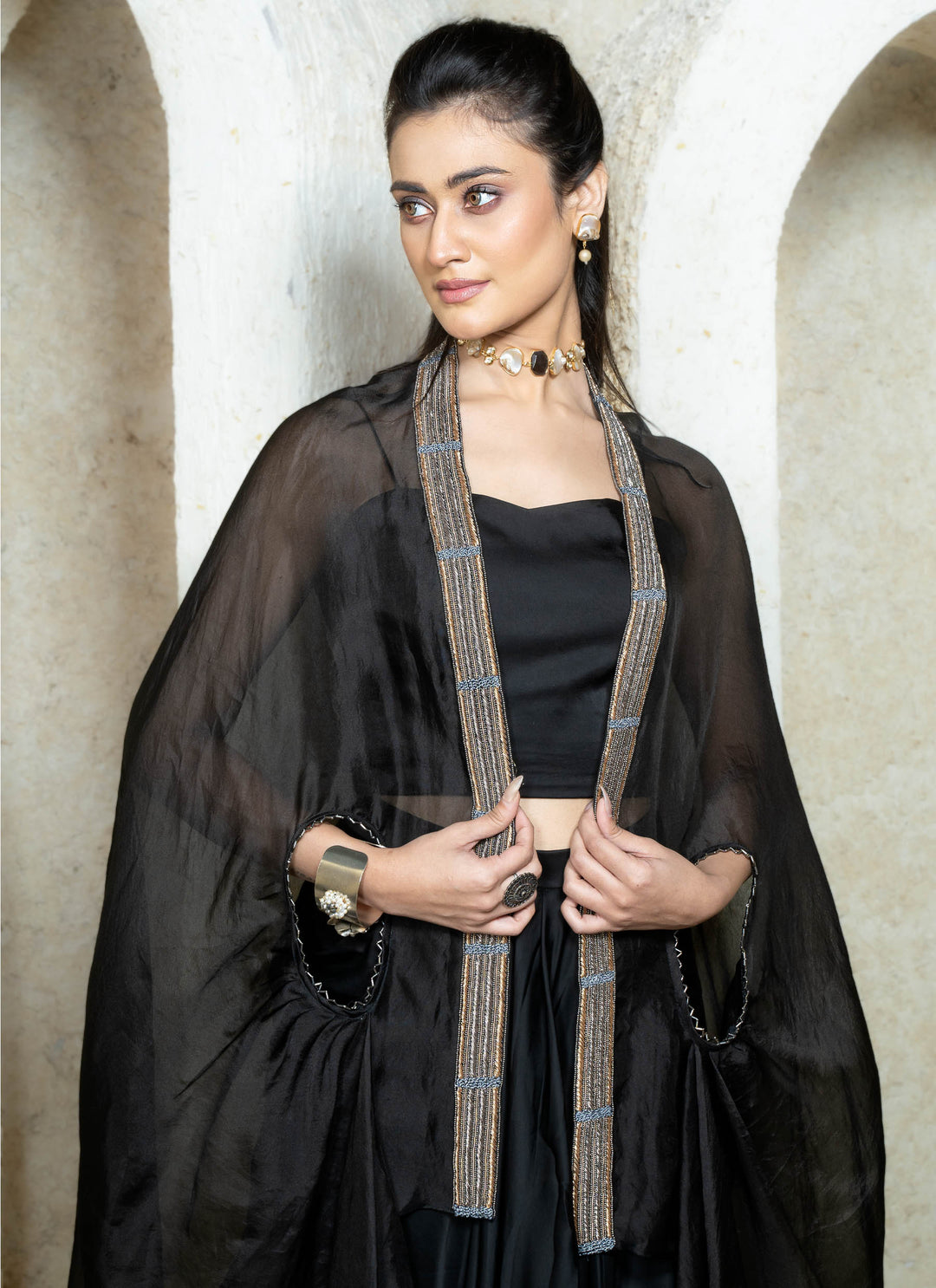 Woman wearing a black drape skirt with embroidered cape in an archway setting