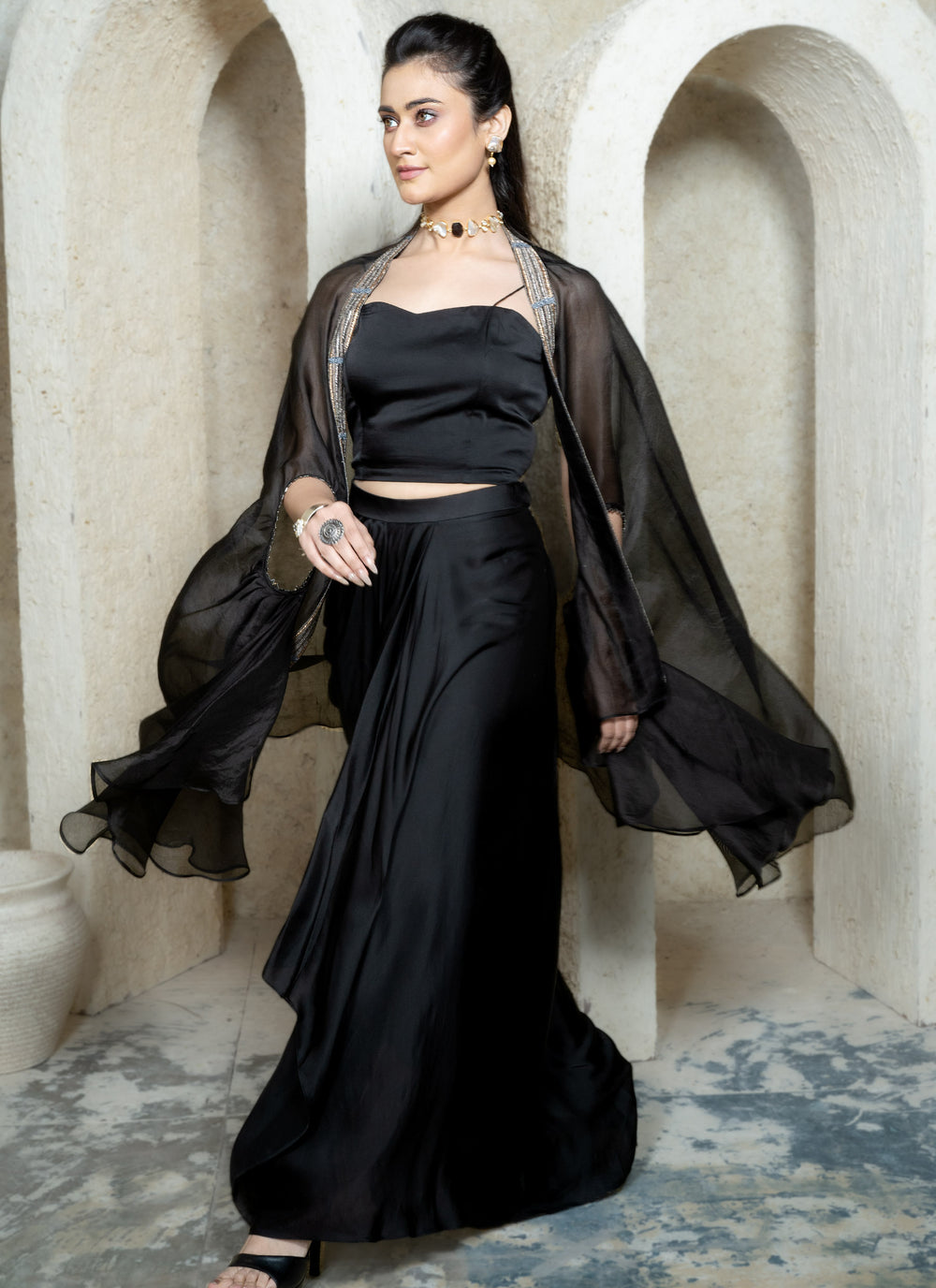 Woman wearing a black drape skirt with embroidered cape and bustier in an archway setting