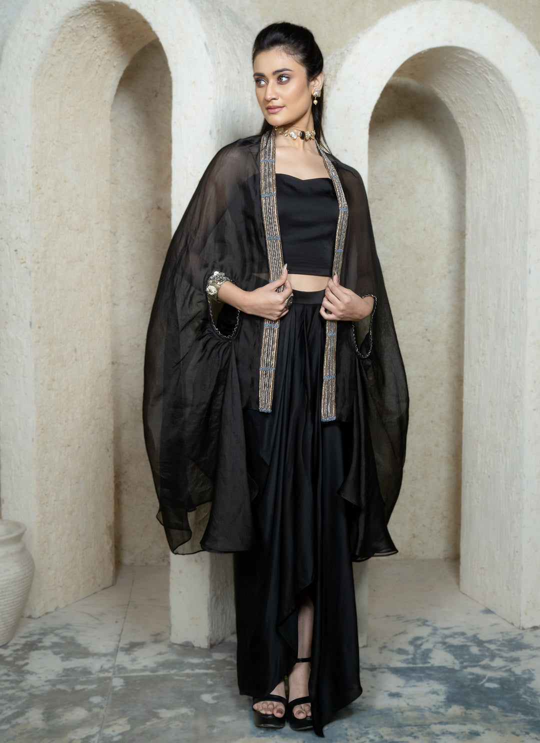 Woman wearing a black drape skirt with embroidered cape and bustier in an archway setting