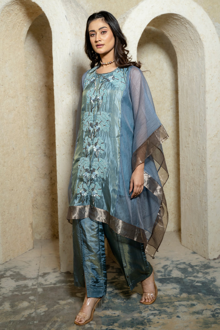 Woman wearing a blue embroidered kaftan set walking in front of a beige background